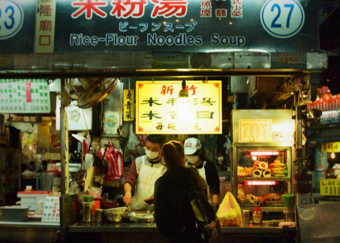 A noodle soup yatai serving a customer at night.